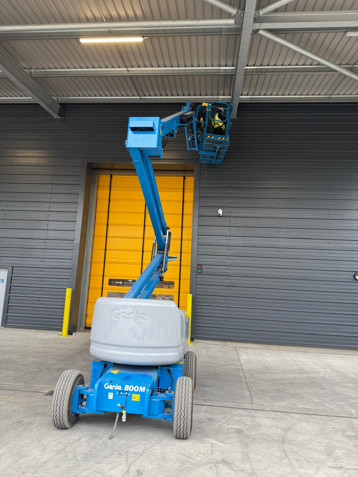 Apex technician installing bird netting from a cherry picker under a roof loading-bay canopy